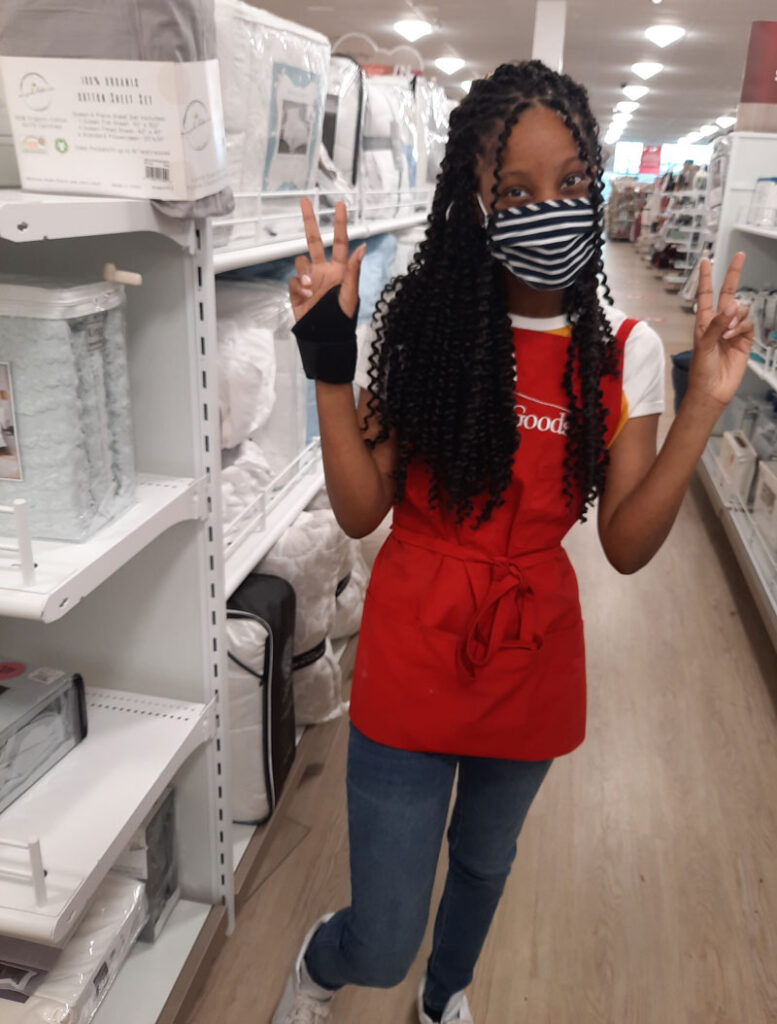 Alpha Group Services, Paige working at Home Goods wearing a mask and making peace signs